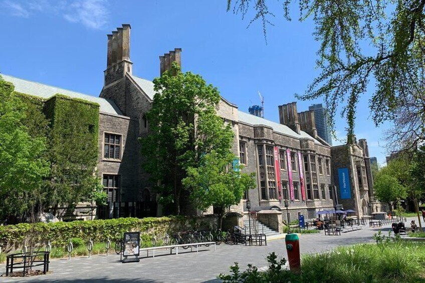 A historic building with ivy-covered walls, a paved courtyard, and a blue entrance. 2