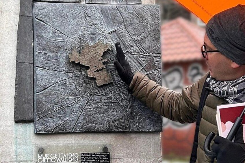 A person examining a damaged wall with a plaque and a torn piece of material. 2