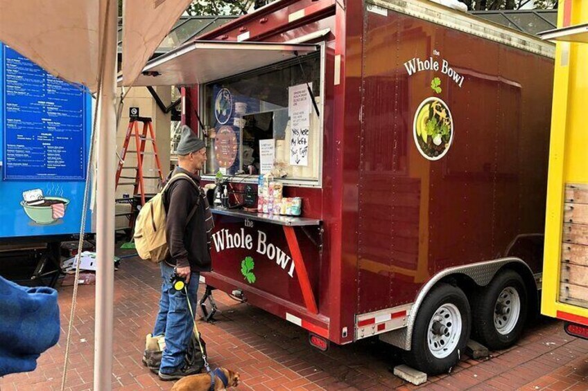 A red food truck with 'The Whole Bowl' branding parked on a brick pavement. 4