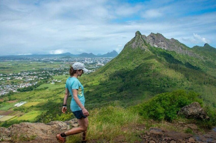 A hiker on a trail with a mountain in the background. 1