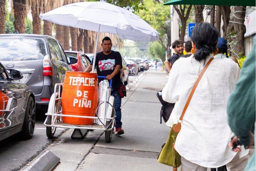 A street scene with a cart labeled 'TEPACHE DE PINA' and a person pushing it. 5