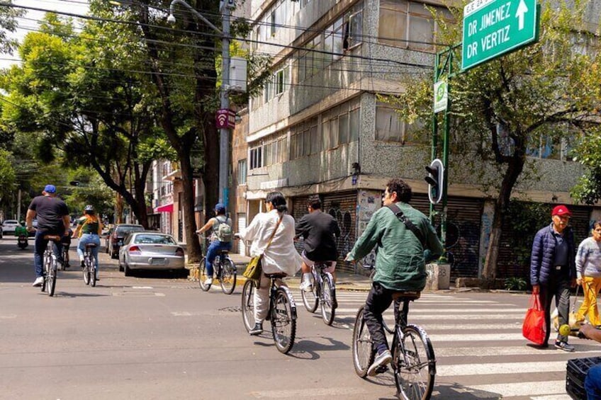 A street scene with cyclists, a crosswalk, and buildings. 5
