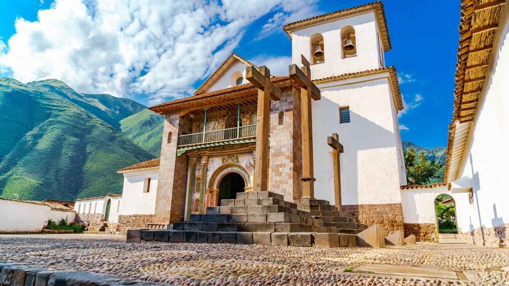 A church with a bell tower, a staircase leading to the entrance, and a mountainous backdrop. 5