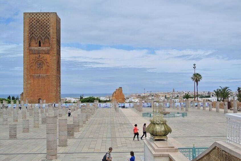 A large square with a prominent tower, a fountain, and a rocky formation in the distance. 3