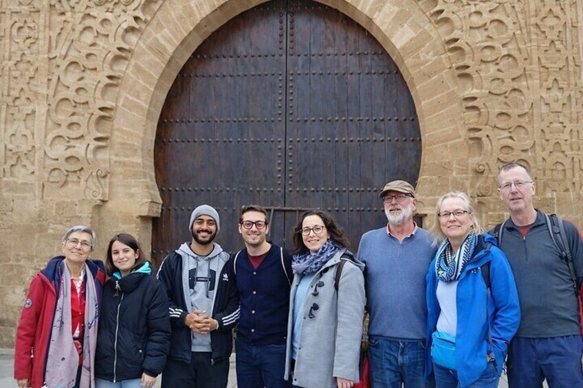 A group of people standing in front of a large, ornate stone door with intricate carvings. 1