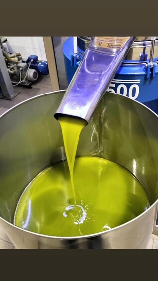 A large metal container with a greenish liquid being poured from a funnel. 5
