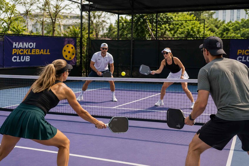 A tennis match on a court with a banner for Hanoi Pickleball Club. 5