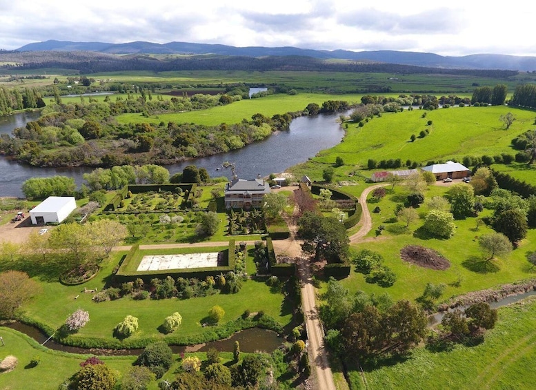 A riverside estate with a large house, a tennis court, and surrounding lush greenery. 5