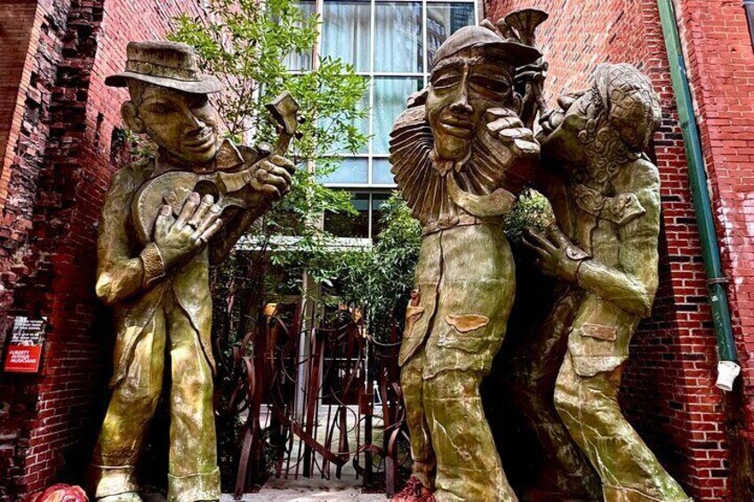 A bronze statue of a man playing a trumpet and a woman with a child in an alleyway. 4