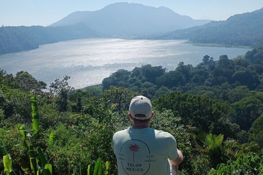 A person overlooking a large body of water surrounded by lush greenery and hills. 4