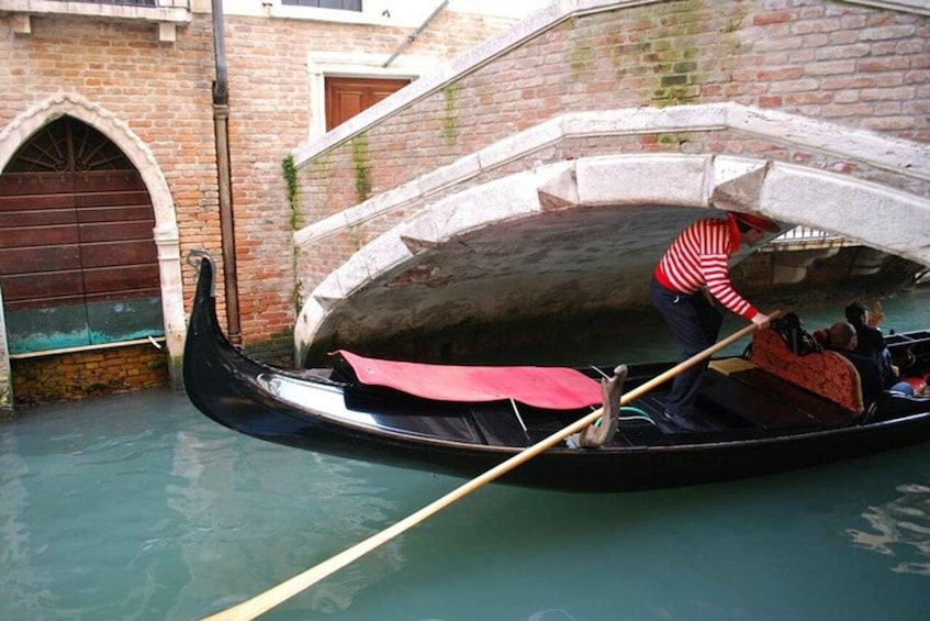 A gondola navigating a narrow canal under a stone bridge in Venice. 2