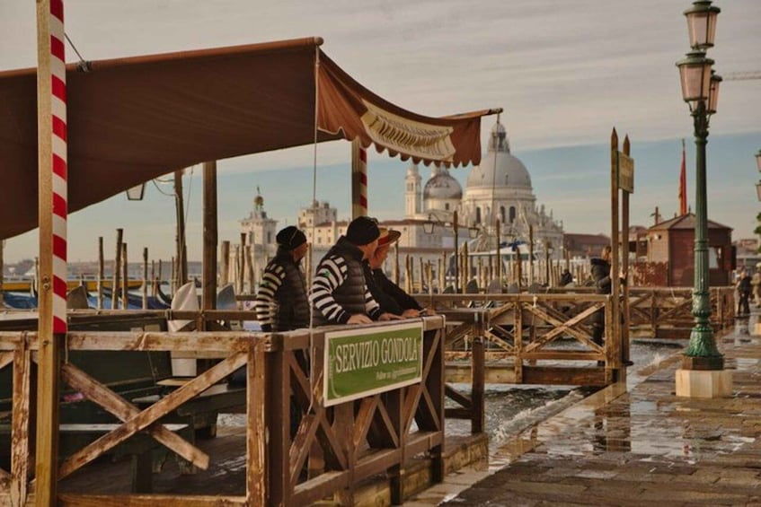 A wooden boat rental service named 'Servizio Gondola' with a view of a large domed building in the background. 4