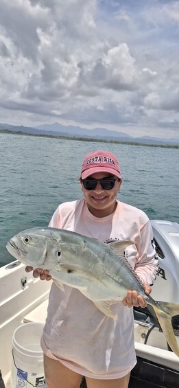 A person holding a fish on a boat with a mountainous landscape in the background. 1