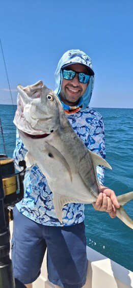 A person holding a large fish on a boat. 3