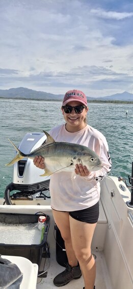 A person holding a fish on a boat with mountains in the background. 2