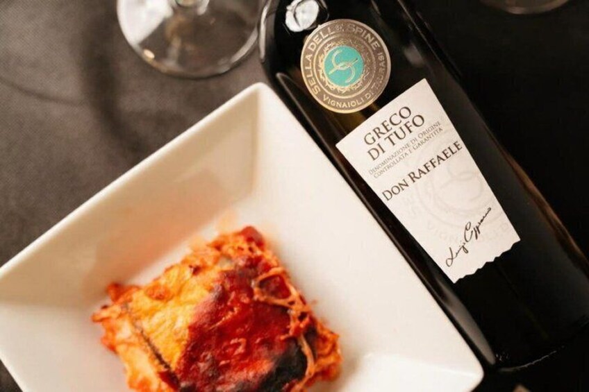 A bottle of Greco di Tufo wine and a plate with a food item. 4
