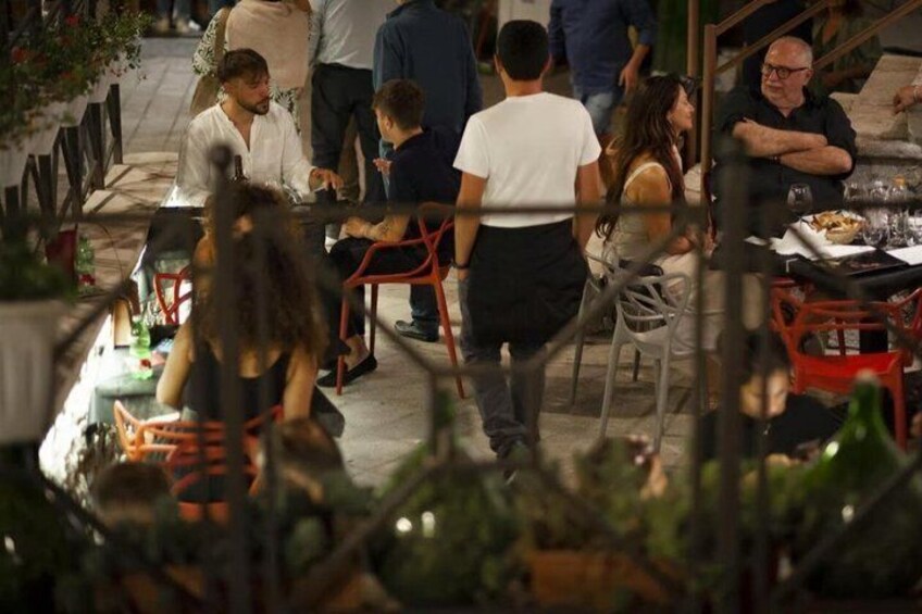 An outdoor dining area with tables and chairs, surrounded by greenery. 5