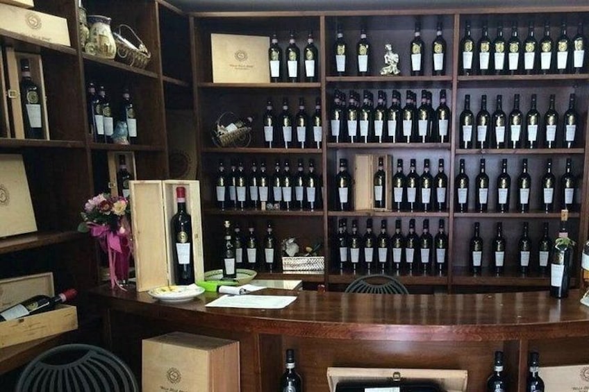 A wine cellar with shelves of wine bottles, wooden boxes, and a table with a vase of flowers. 3