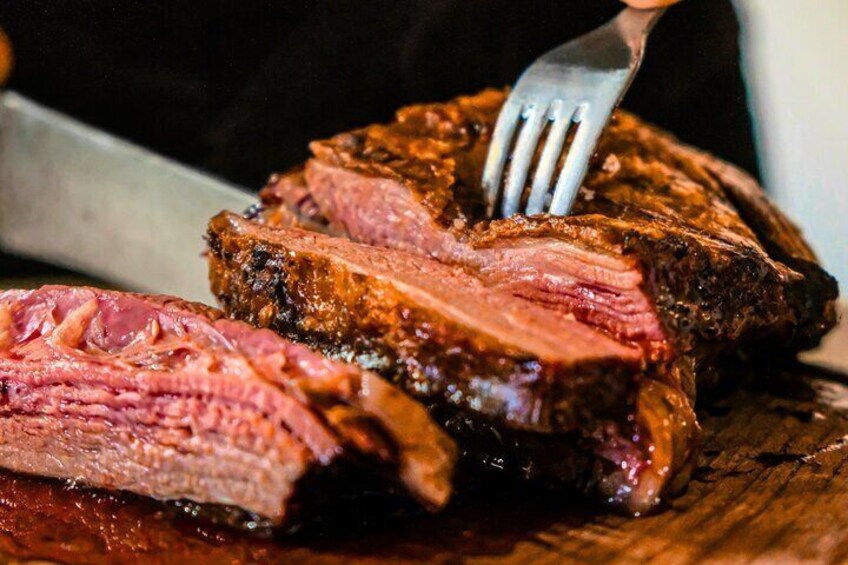 A steak with a fork on a wooden cutting board. 1