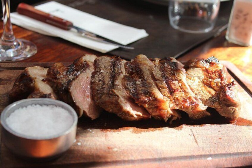 Sliced grilled meat on a wooden board with a salt shaker. 5