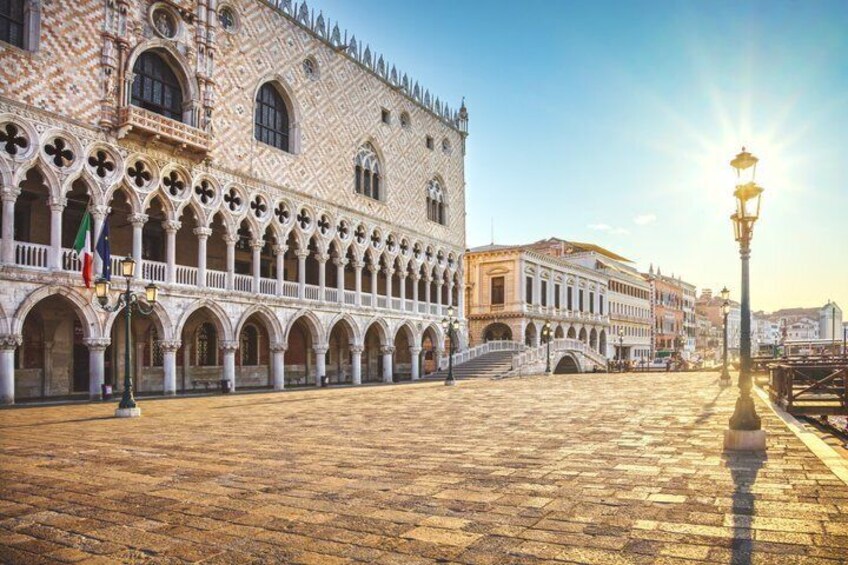 A historic square with a patterned building, a fountain, and a street lamp. 5