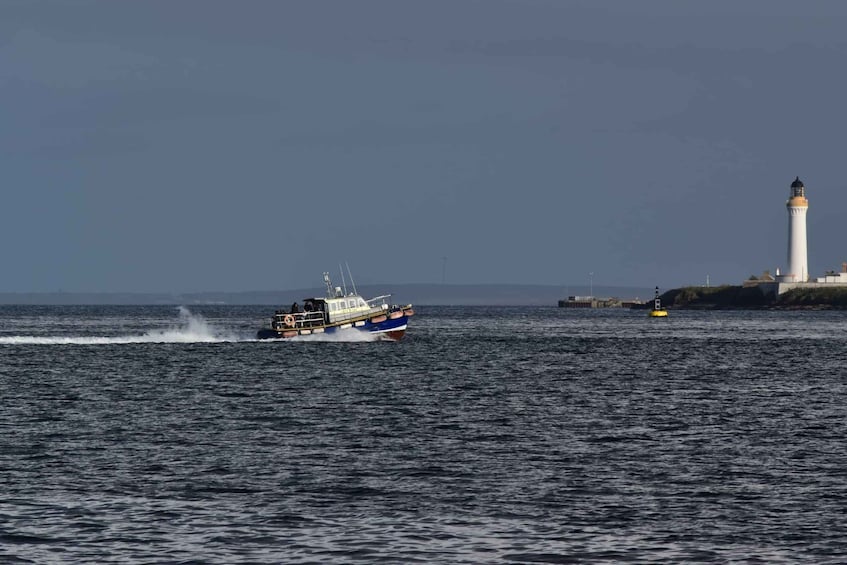 A boat speeding across a body of water with a lighthouse in the background. 2