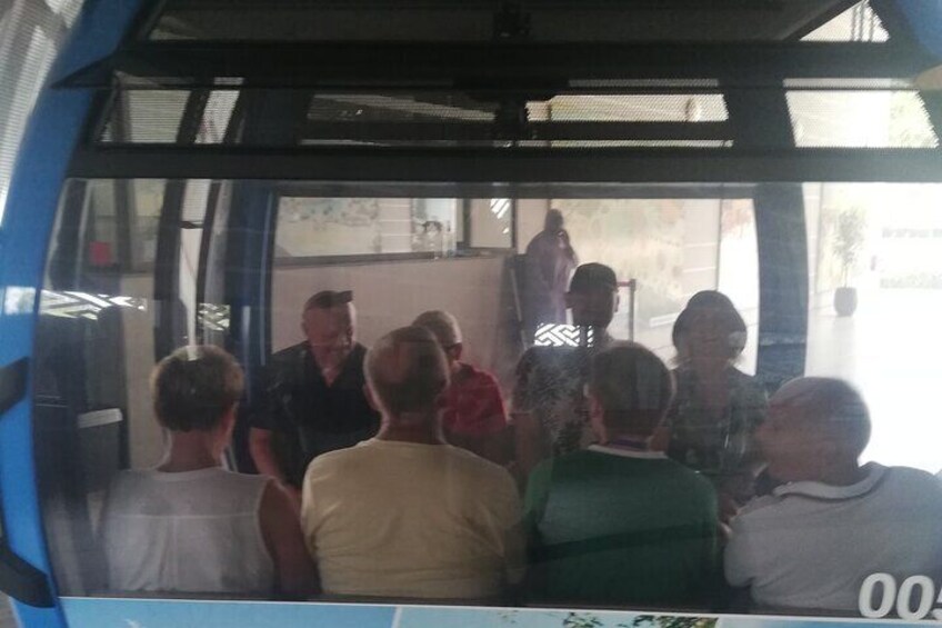 A group of people inside a vehicle, possibly a bus, with a person standing at the back. 5