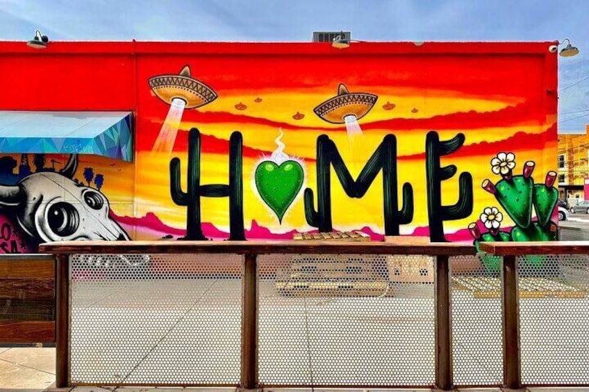A colorful mural with the word 'HOME' and a cactus. 5