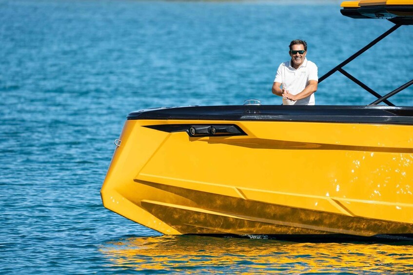 A yellow boat on calm water with a person standing on the deck. 2