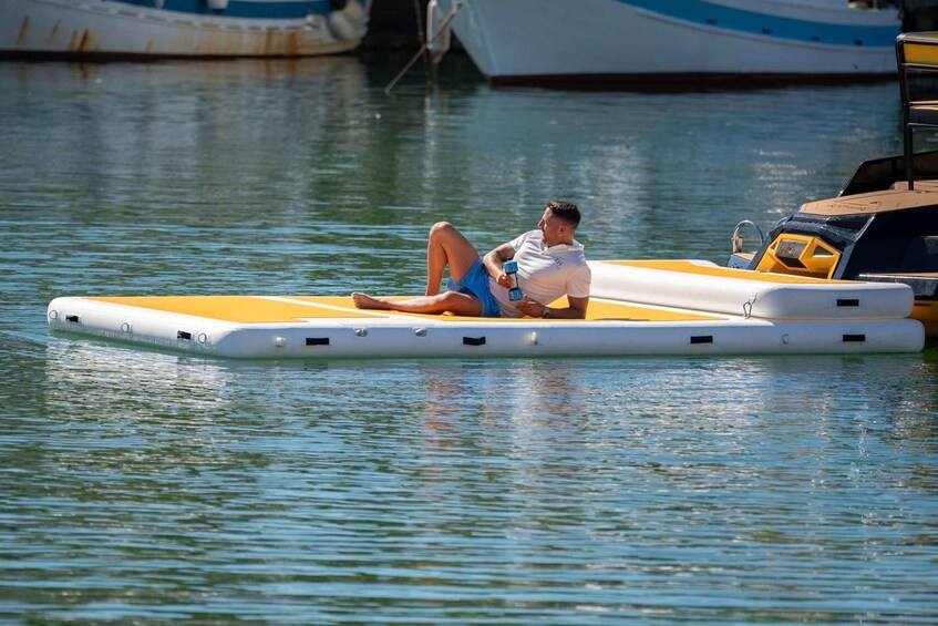 A person relaxing on a floating platform in calm water, surrounded by boats. 5