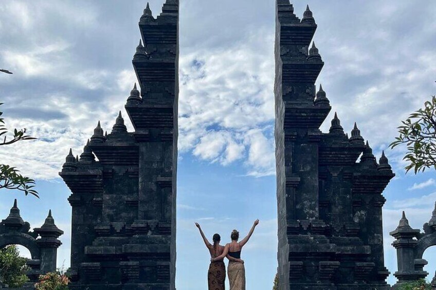 A person standing between two ancient stone structures with pointed tops, under a partly cloudy sky. 1