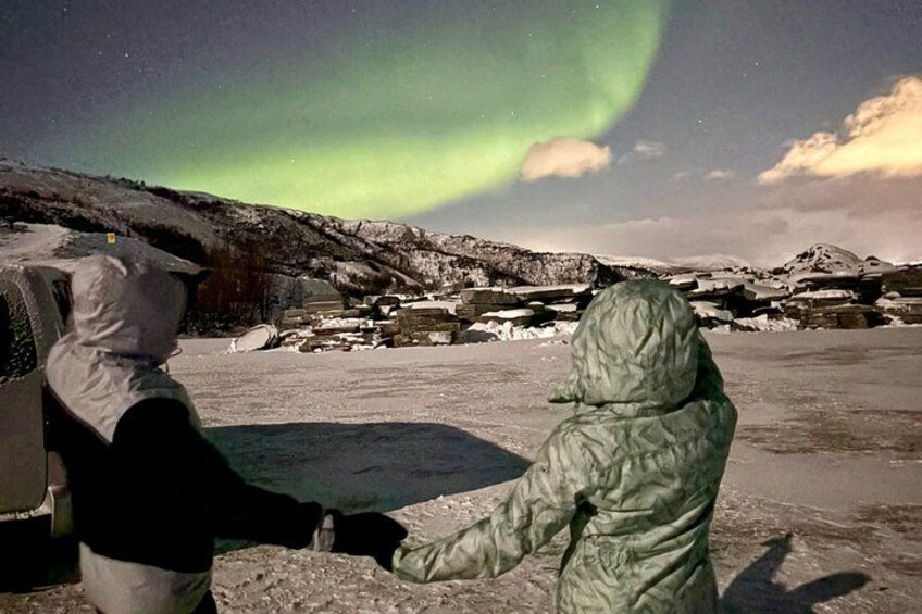 Two people observing the Northern Lights in a snowy landscape. 2