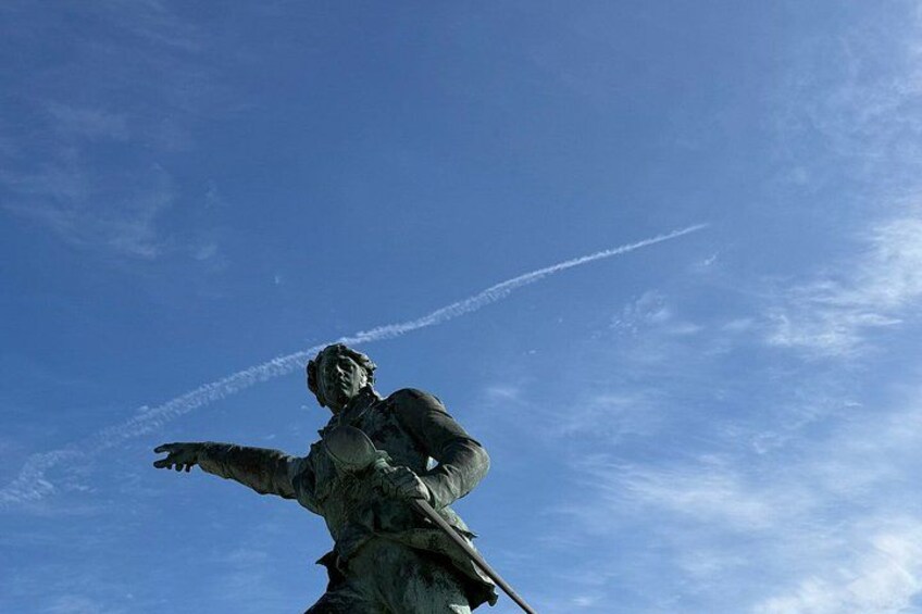 A statue of a person with outstretched arms against a clear blue sky. 2