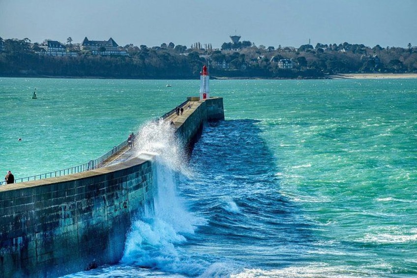 A lighthouse on a pier with waves crashing against it. 3