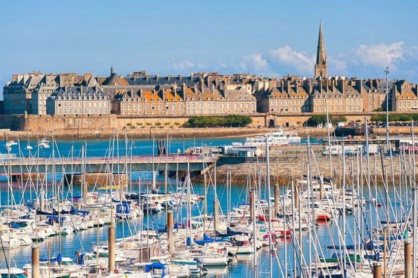 A harbor with numerous boats docked, a historic building complex, and a prominent church spire in the background. 3