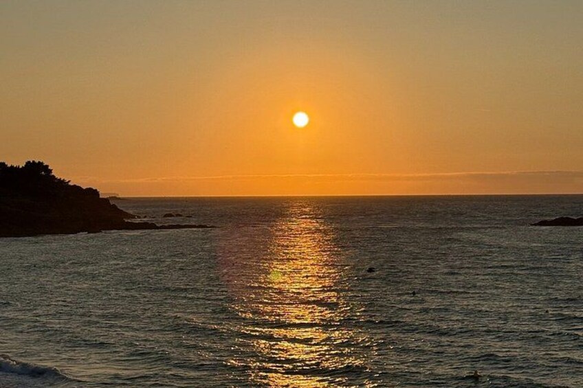 A sunset over the ocean with a silhouette of a landmass on the left. 5