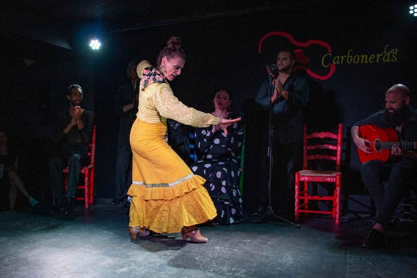 A person dancing on a stage with a guitar player and a microphone stand in the background. 3