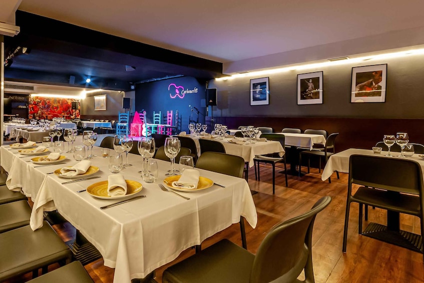 A restaurant with tables set for dining, a neon sign, and framed pictures on the wall. 1