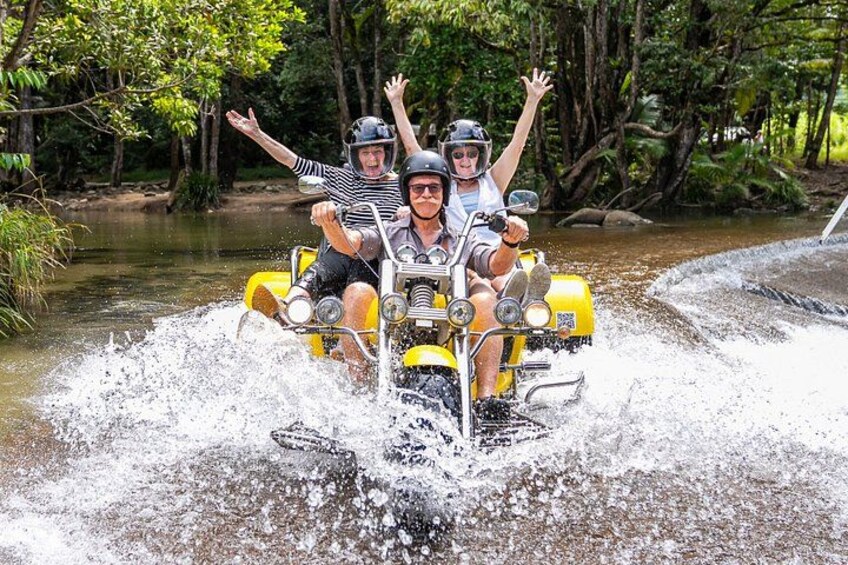Two people on a yellow watercraft in a river surrounded by trees. 1
