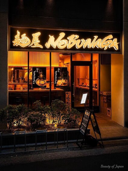 A restaurant with illuminated signage and a menu board outside. 2