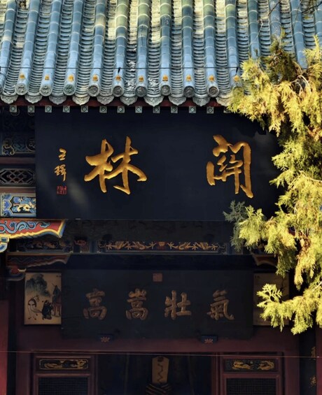 A traditional building with a tiled roof and a sign with golden Chinese characters. 2