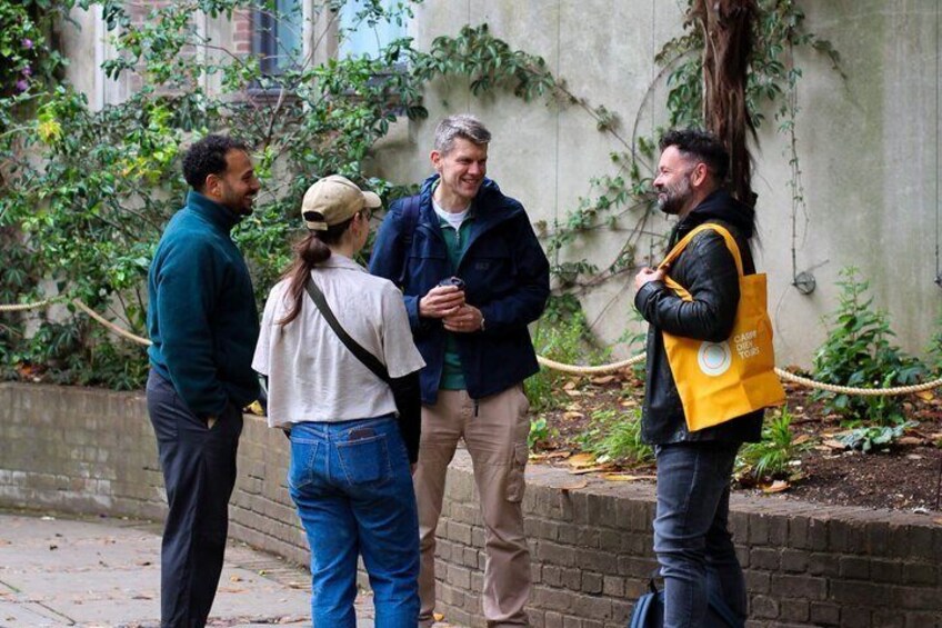 Four people standing on a sidewalk, conversing. 2