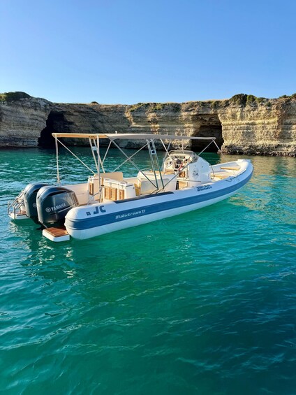 A small motorboat named 'Main-stream 33' anchored near a rocky cliff with a cave entrance. 1