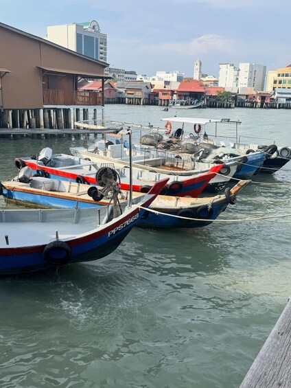 A row of colorful boats docked at a pier with buildings in the background. 5