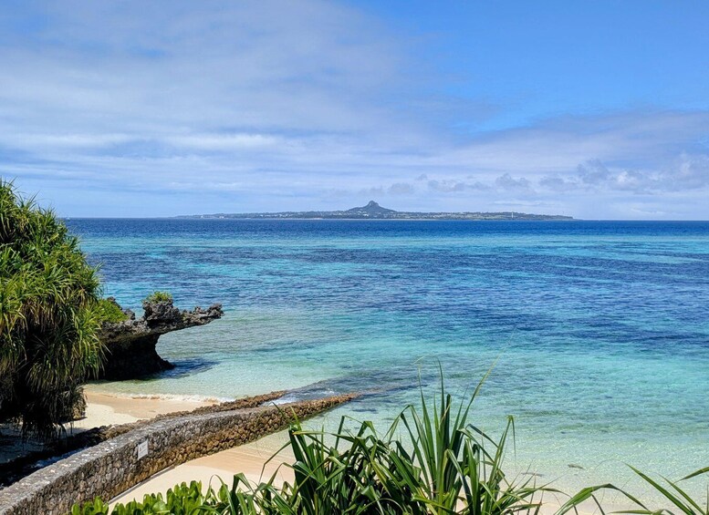 A coastal landscape with clear turquoise waters, a sandy beach, and a rocky outcrop. 5