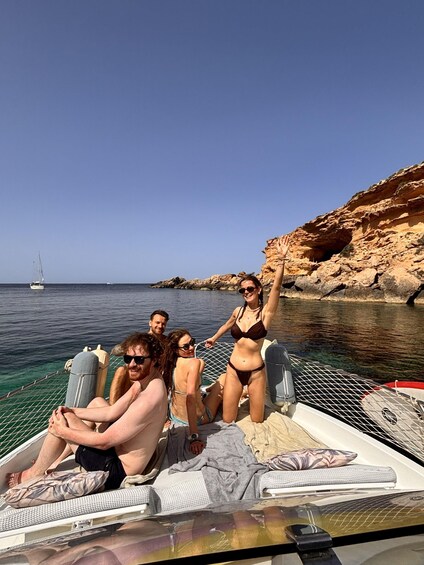 A group of people on a boat near rocky cliffs and clear water. 3