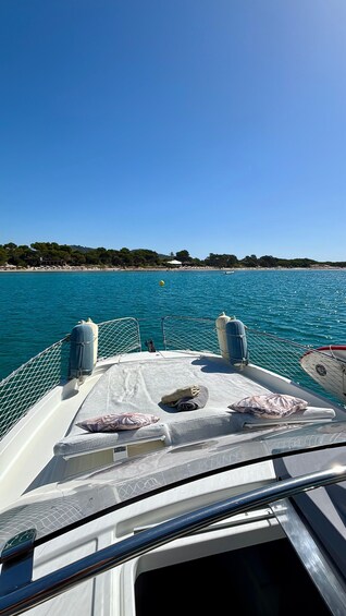 A boat's deck with a netted railing, cushions, and a view of a calm sea and distant shoreline. 2