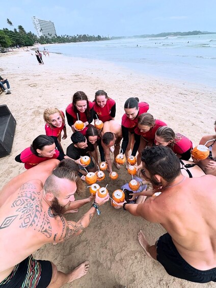 A group of people on a beach, some holding coconuts. 5