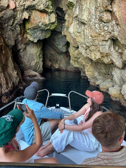 A group of people on a boat near a rocky cave entrance. 2