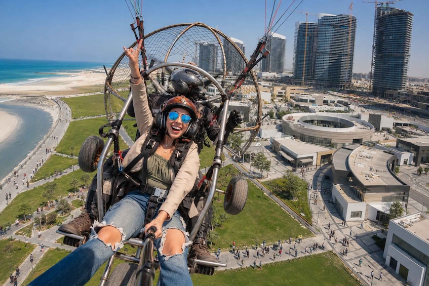 A person in a hang glider with a cityscape and beach in the background. 1